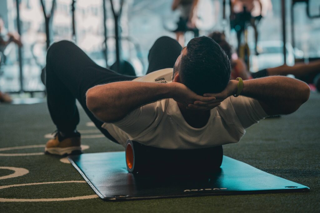 An athlete practicing thoracic extensions on a foam roller to address lower back pain from riding a mountain bike, using the Alignment Protocol framework.